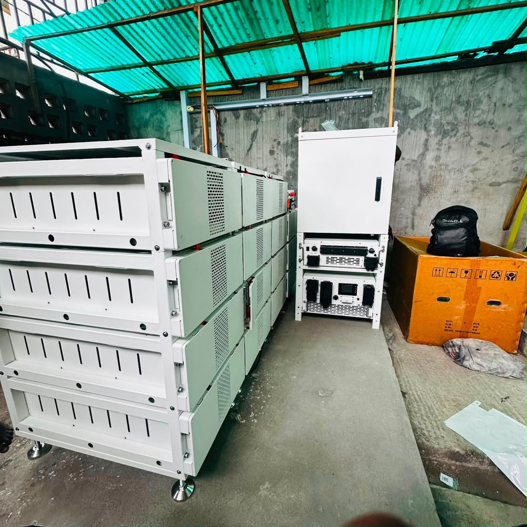 Industrial battery racks and power equipment beneath a green canopy at the factory installation